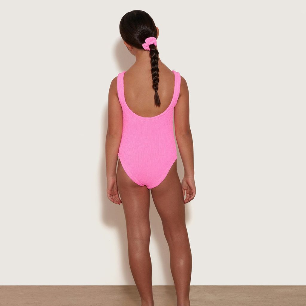Girl from the back wearing the Hunza G Kids Classic Swimsuit in Bubblegum for girls aged 7 - 12 years