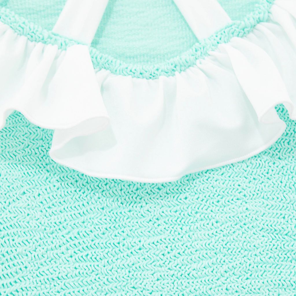 Image of the back of the Baby Lara swimsuit from Hunza G in a metallic mint colour way with a white bow on the back, for 3 - 6 year old girls.